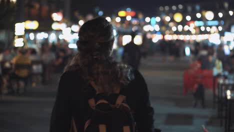 vrouw die door een drukke nachtmarkt loopt.