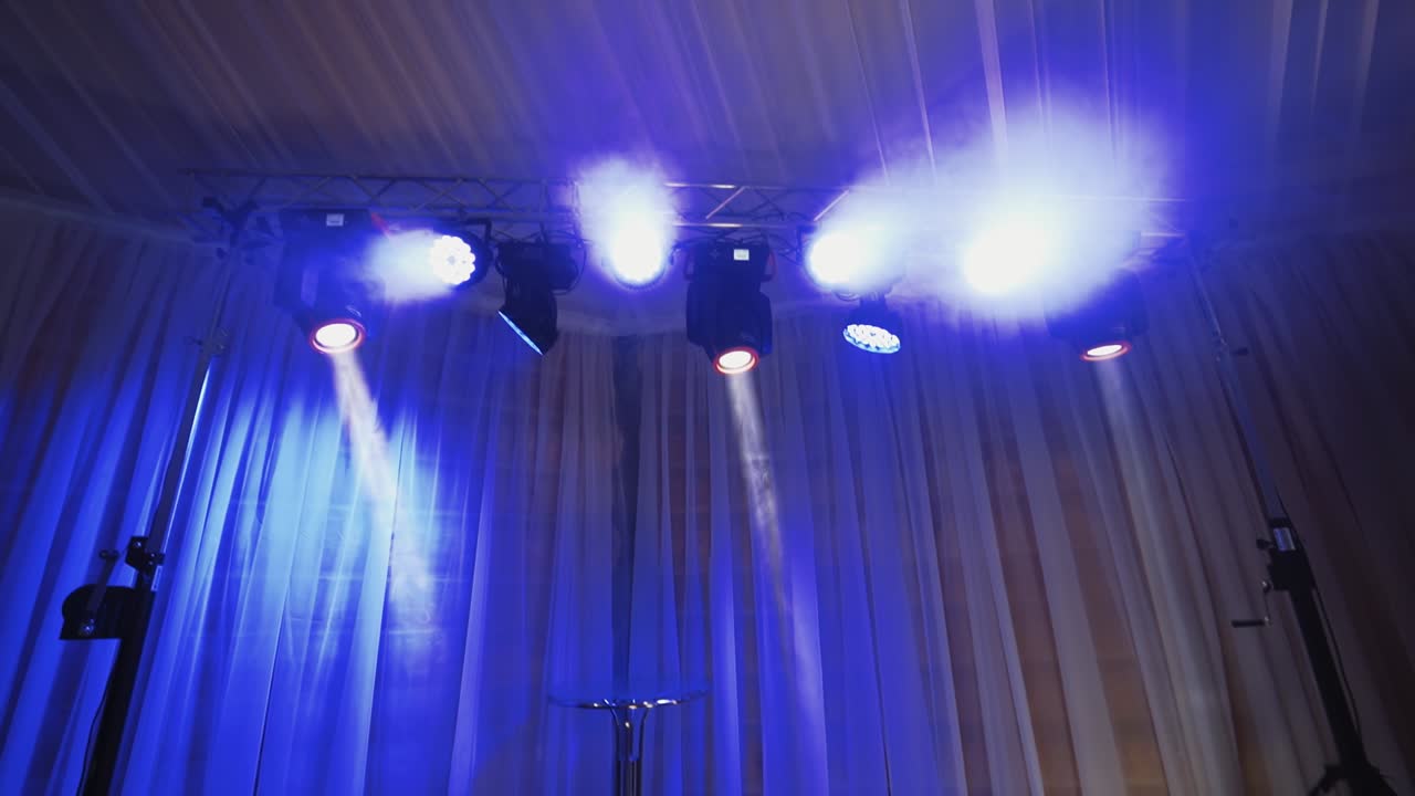 Animation of stage lights frame. Bright shiny lights flashing with blue from spotlight projectors in the dark. Led lighting equipment.