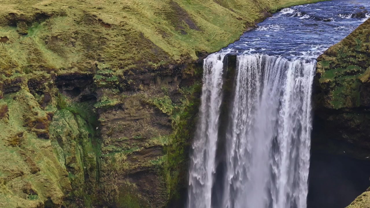 Fugle flyver forbi Skógafoss-vandfaldet på Island, langsom luftpanorering