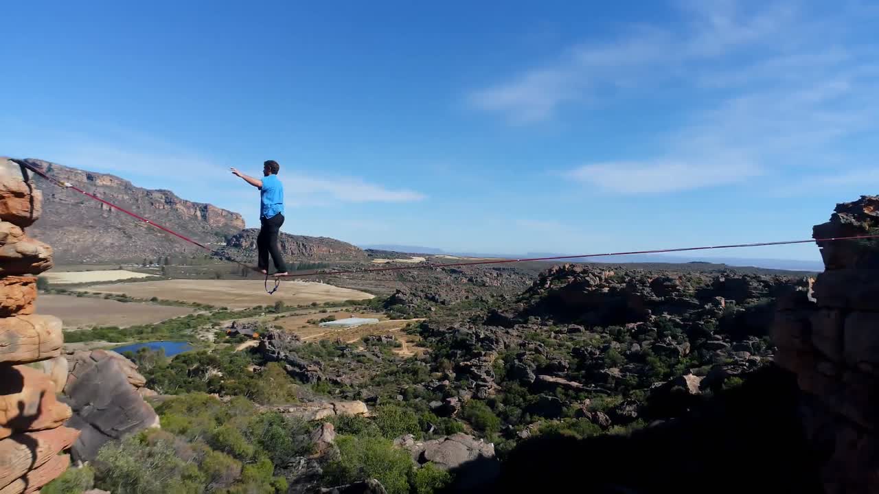 hombre caminando en una cuerda sobre las montañas rocosas 4k