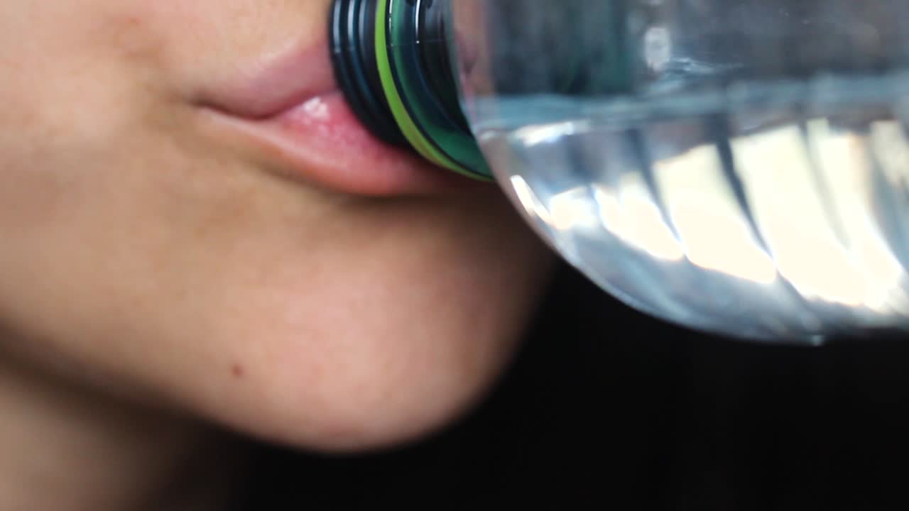 primer plano de una mujer joven sana sosteniendo una botella de agua bebiendo agua mineral pura transparente y fresca, una mujer hidratando la sed con agua potable
