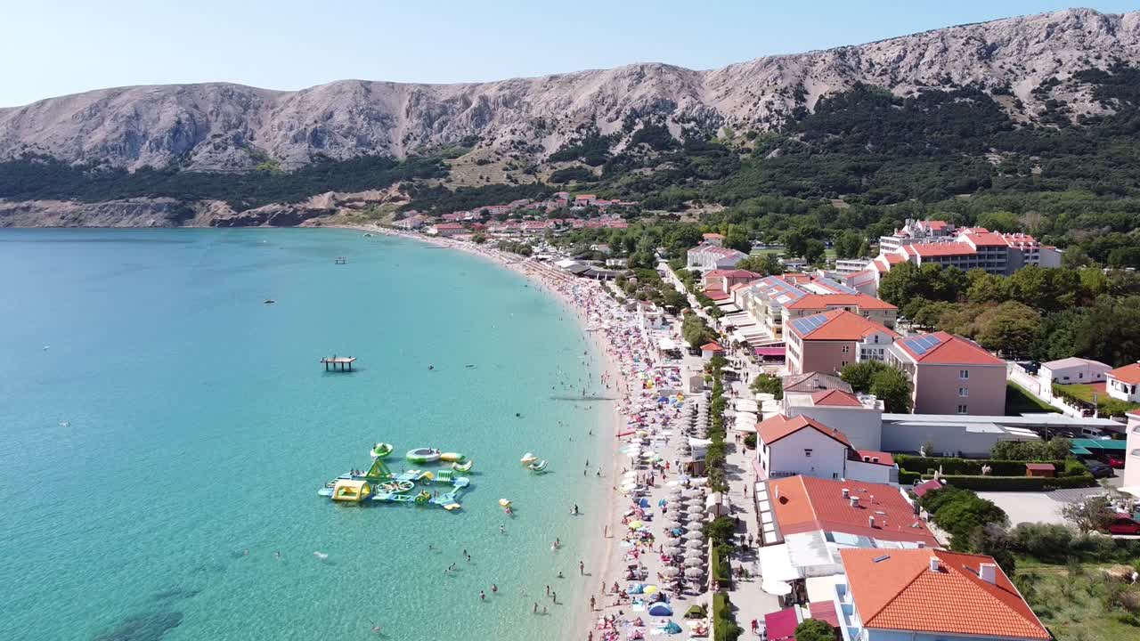pláž baška, ostrov krk, chorvatsko - vzdušný pohled na turisty, bulvár, ležadla a vodní hřiště za slunečného letního dne