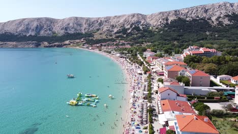 playa de baška, isla de krk, croacia - vista aérea de turistas, bulevar, tumbonas y juegos acuáticos en un día soleado de verano