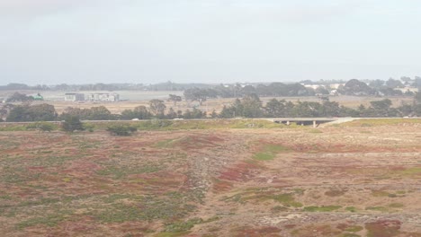 open skies and rugged terrain surround fort ord, with a faint glimpse of cars rolling along highway 1.