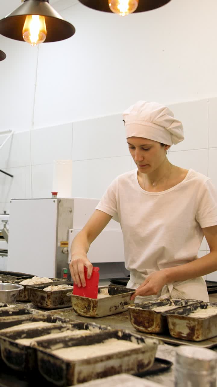 Fornaia che prepara l'impasto nelle teglie in una cucina professionale