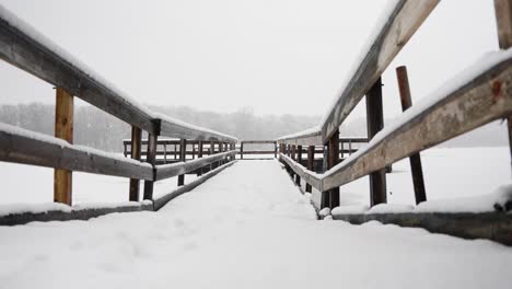 low shot of a snow covered bridge on a frozen lake on a snowy winter day