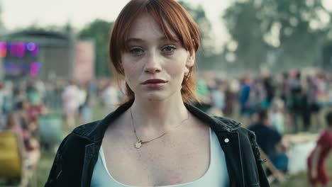 portrait of ginger haired young caucasian woman at music festival showing neutral emotions.