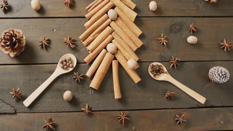 video of christmas tree, pine cones and spices on wooden background