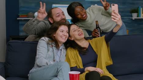 Group-of-mixed-race-people-taking-pictures-with-phone-while-sitting-on-couch