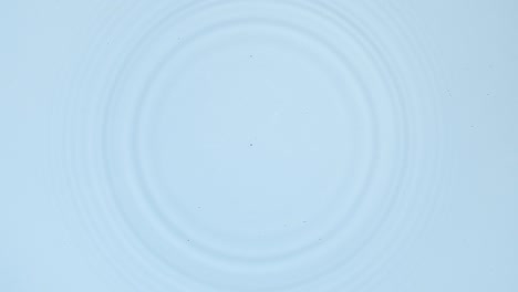 white drop falls down creating circles on water surface