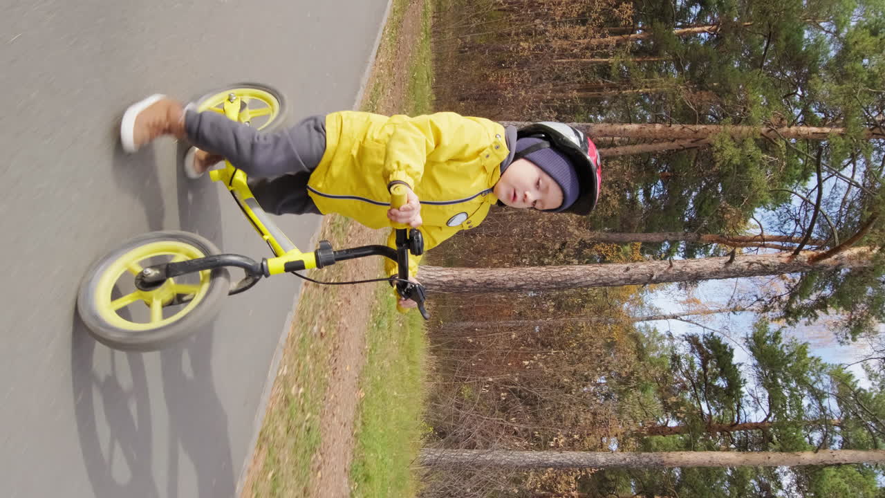 Boy riding a balance bike in the park during autumn
