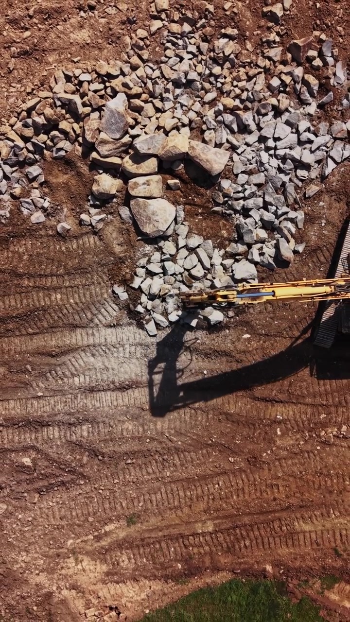 Heavy machinery clears rocks at a construction site in daylight