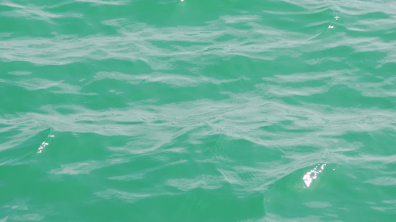 Calm ocean waves ripple under bright sunlight in Phuket, Thailand, creating a serene and tranquil atmosphere