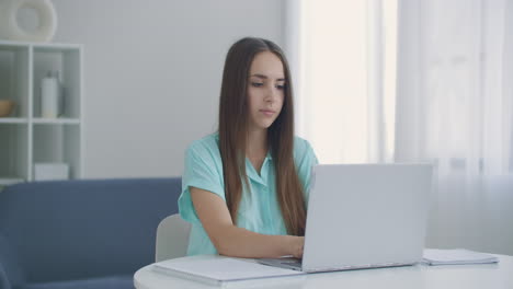 focused business woman entrepreneur typing on laptop doing research. young female professional using computer sitting at home office desk. busy worker freelancer working on modern tech notebook device