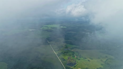 Vast-green-landscapes-partly-shrouded-in-cloud-mist,-aerial-view