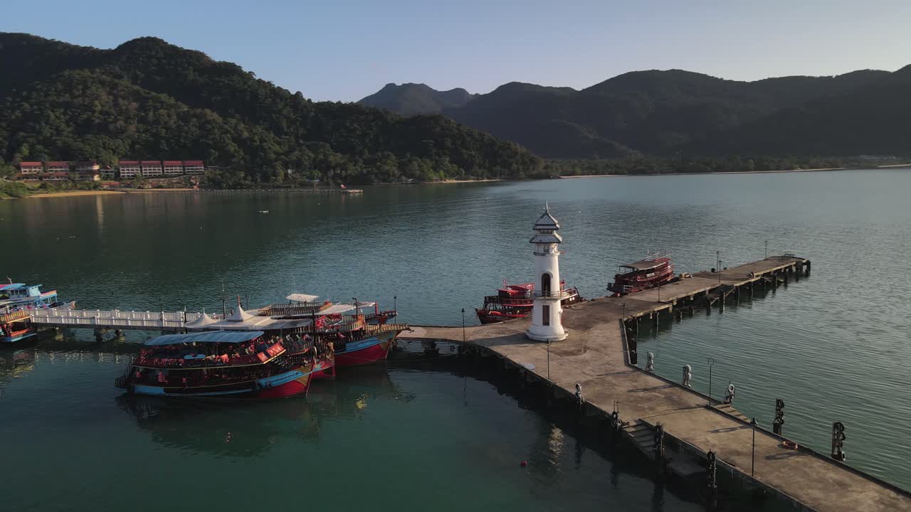 toma de órbita aérea lenta del muelle de bang bao en koh chang, tailandia con el sol golpeando el faro