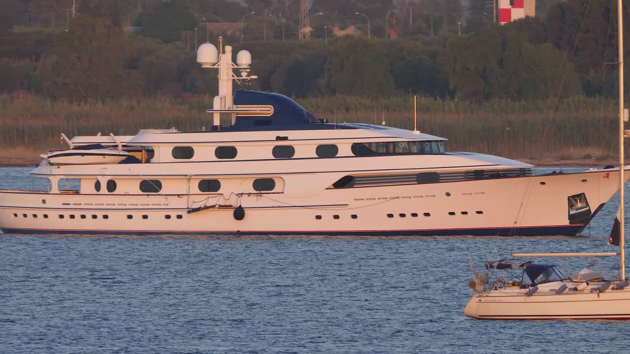 Piccola barca a vela e grande yacht ancorati vicino a Siracusa