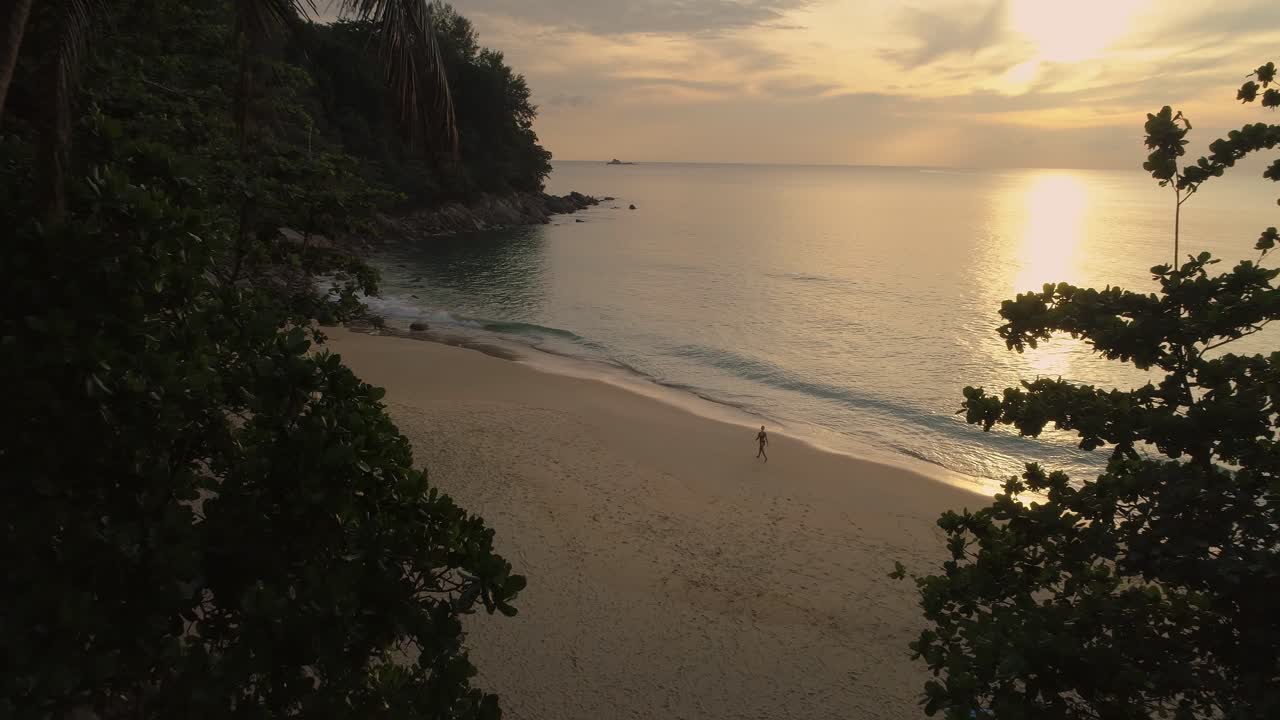 Donna in bikini che cammina su una spiaggia tropicale durante un tramonto magico, Thailandia