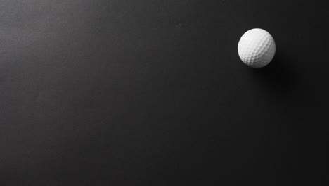 Close-up-of-golf-ball-on-black-background,-copy-space,-slow-motion