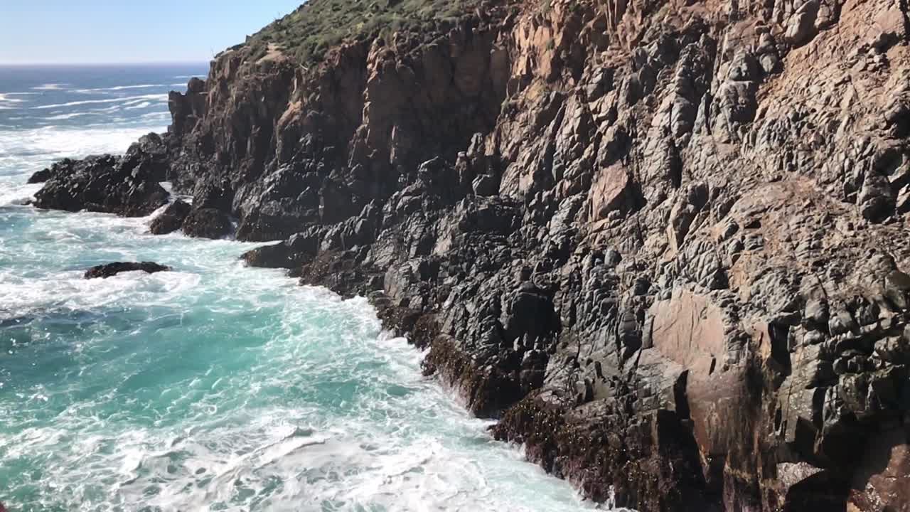 una vista de las olas del mar están golpeando las rocas de una montaña