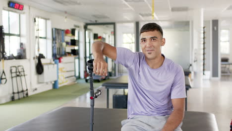 man in rehabilitation center sitting with crutches, smiling and looking content