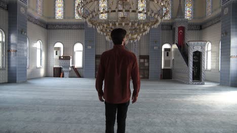 a muslim young man walks inside the mosque, behind a shot, muslims who go to historical and holy places pray