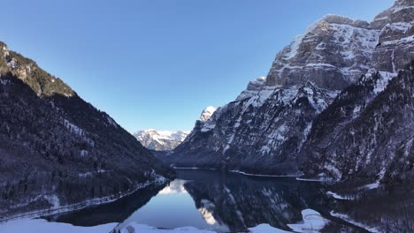 snowy alps mirrored on klöntalersee in klöntal, switzerland, serene winter mountain view