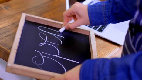 propietaria femenina escribiendo en la pizarra en el café 4k