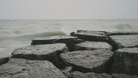 sea waves crash on the breakwater rocks and stones during daytime