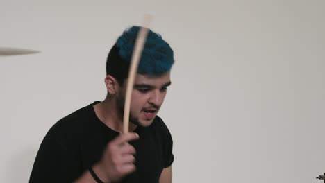 un tipo de cabello azul toca la batería.