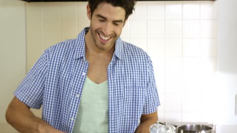 hombre sonriente mezclando una ensalada en la cocina