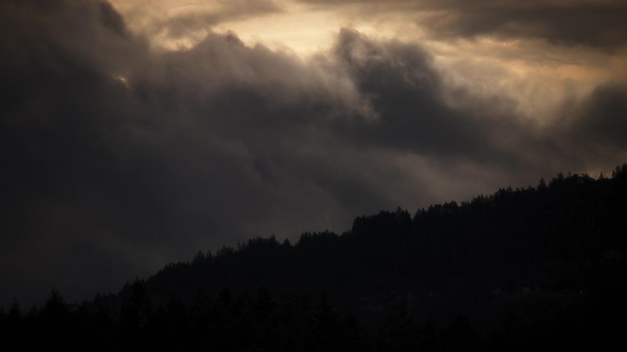 Nuvens tempestuosas dramáticas movendo-se acima da montanha ao nascer do sol.