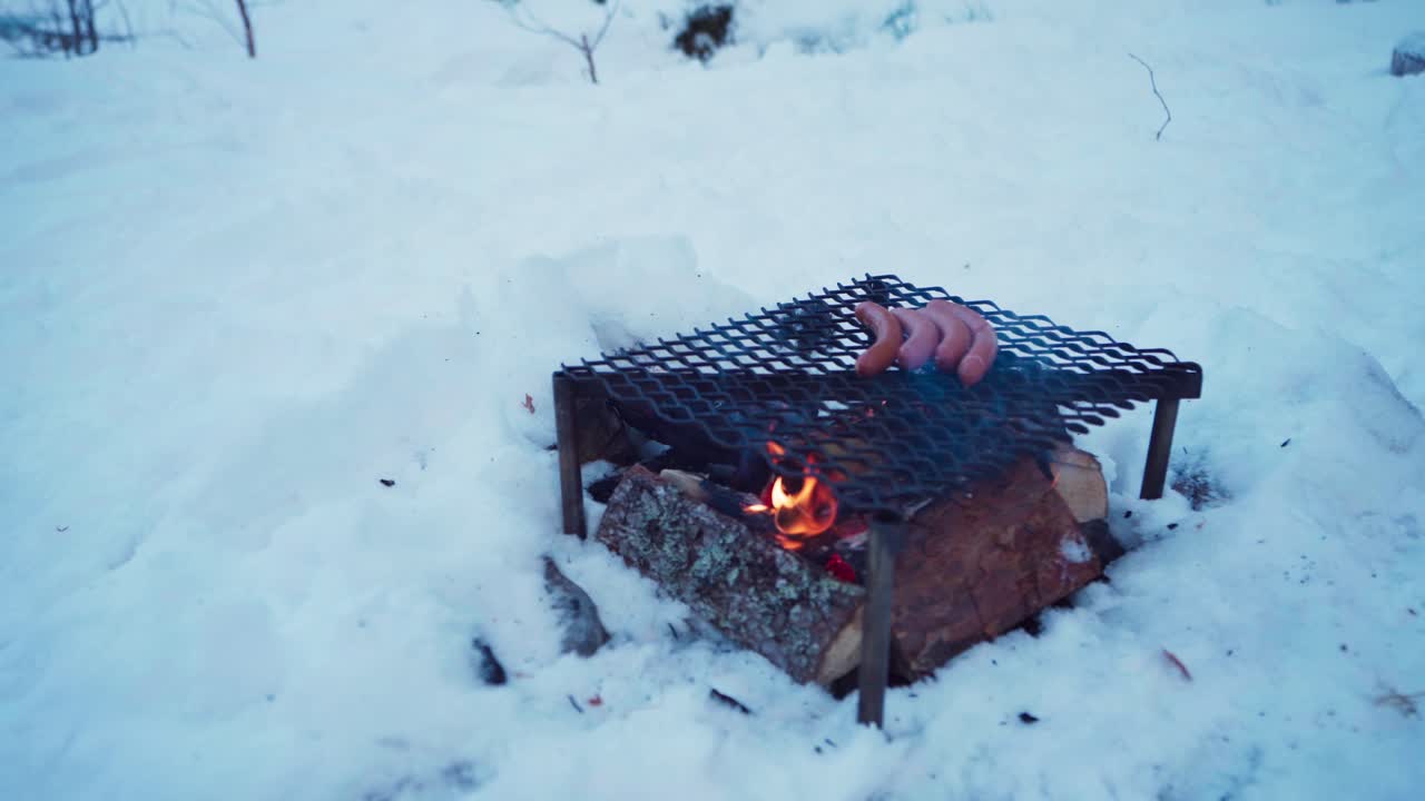한 사람 이 겨울 에 철 판 을 이용 하여 불  ⁇  을 타고 밖 에서 요리 하고 있다