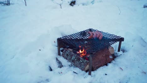 a person is cooking outside over a fire wood using iron pan during winter