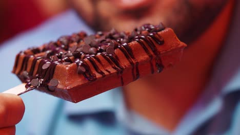 closeup of man eating chocolate waffle