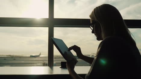 mujer usando una tableta en un aeropuerto