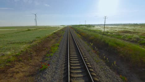 train tracks through scenic countryside with wind turbine