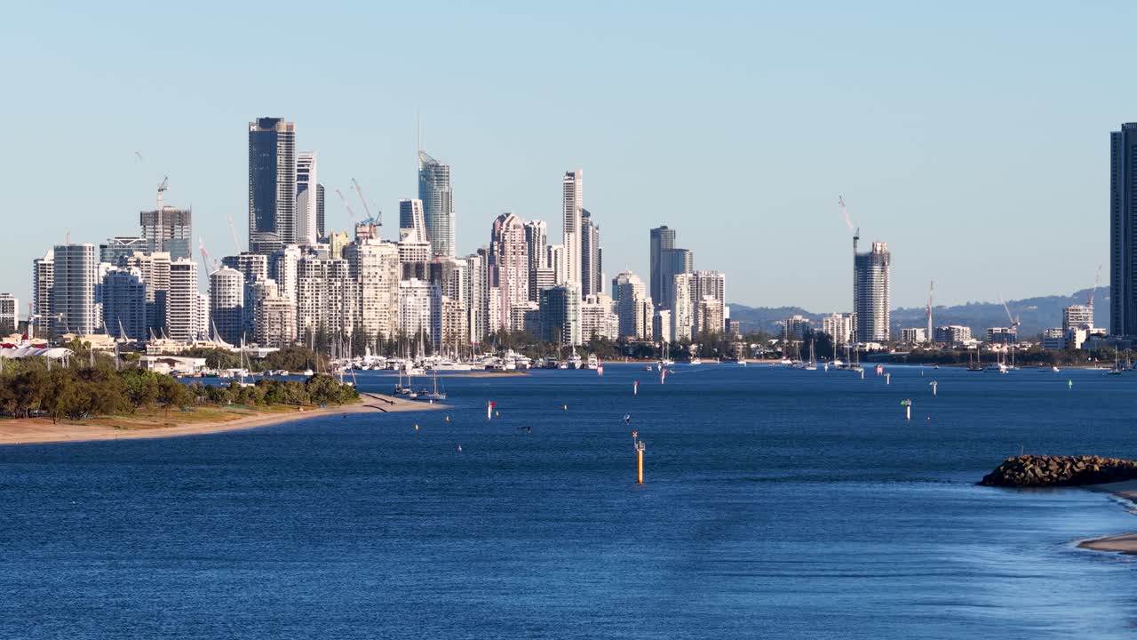 Drone footage captures the Gold Coast skyline with vibrant sunset lighting, showcasing the city's iconic skyscrapers and coastal beauty