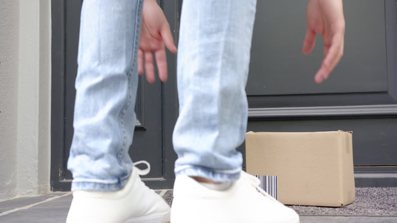 두 인종의 남자가 앞 문 밖의 카드보드 상자에 패키지를 배달하는 낮은 섹션, 느린 모션