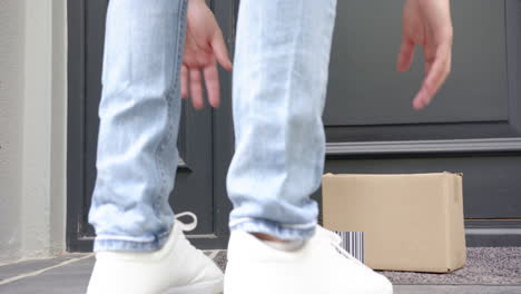 low section of biracial man delivering package in cardboard box outside front door, slow motion