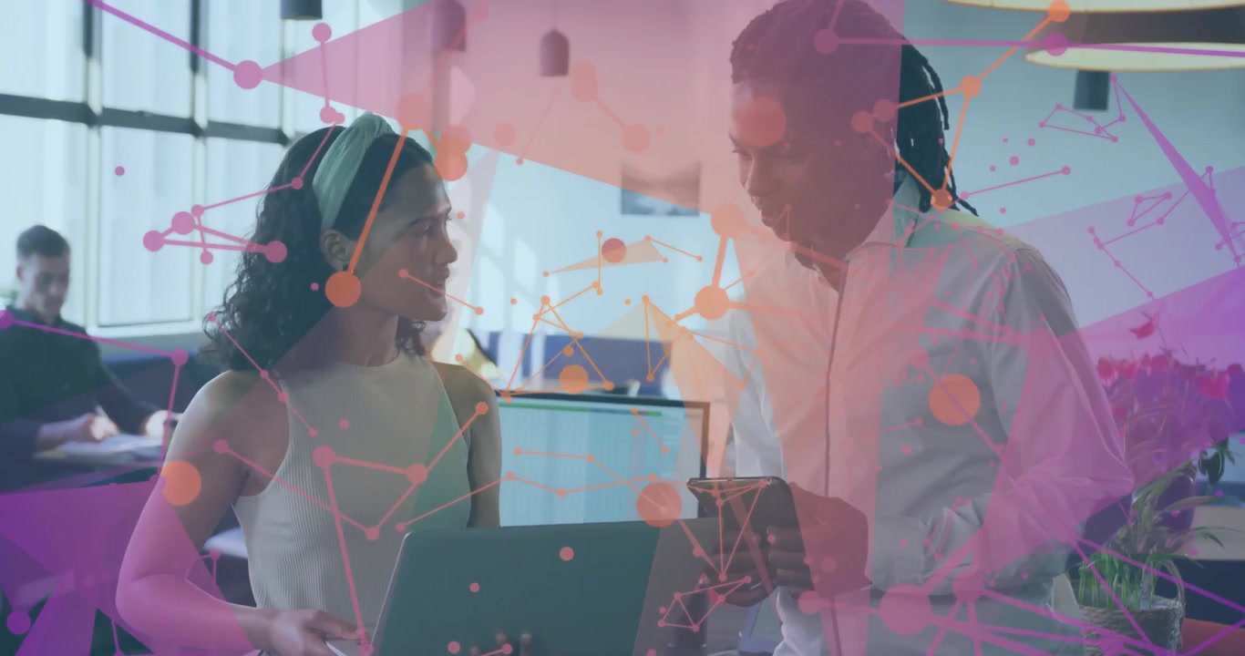 Colleagues opening laptop and tapping tablet, generating network overlay examining business data