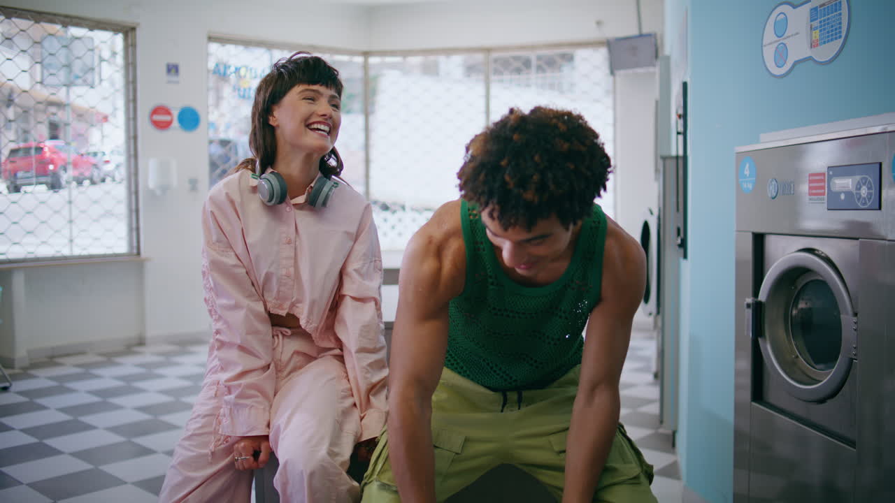 dos amigos felices riendo en una lavandería pública. adolescentes despreocupados lavando