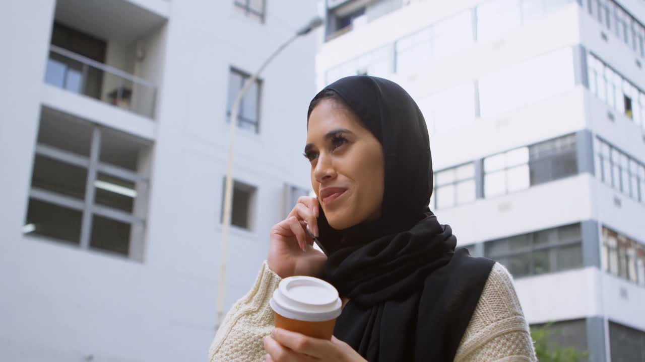 Woman drinking coffee while talking on mobile phone 4k