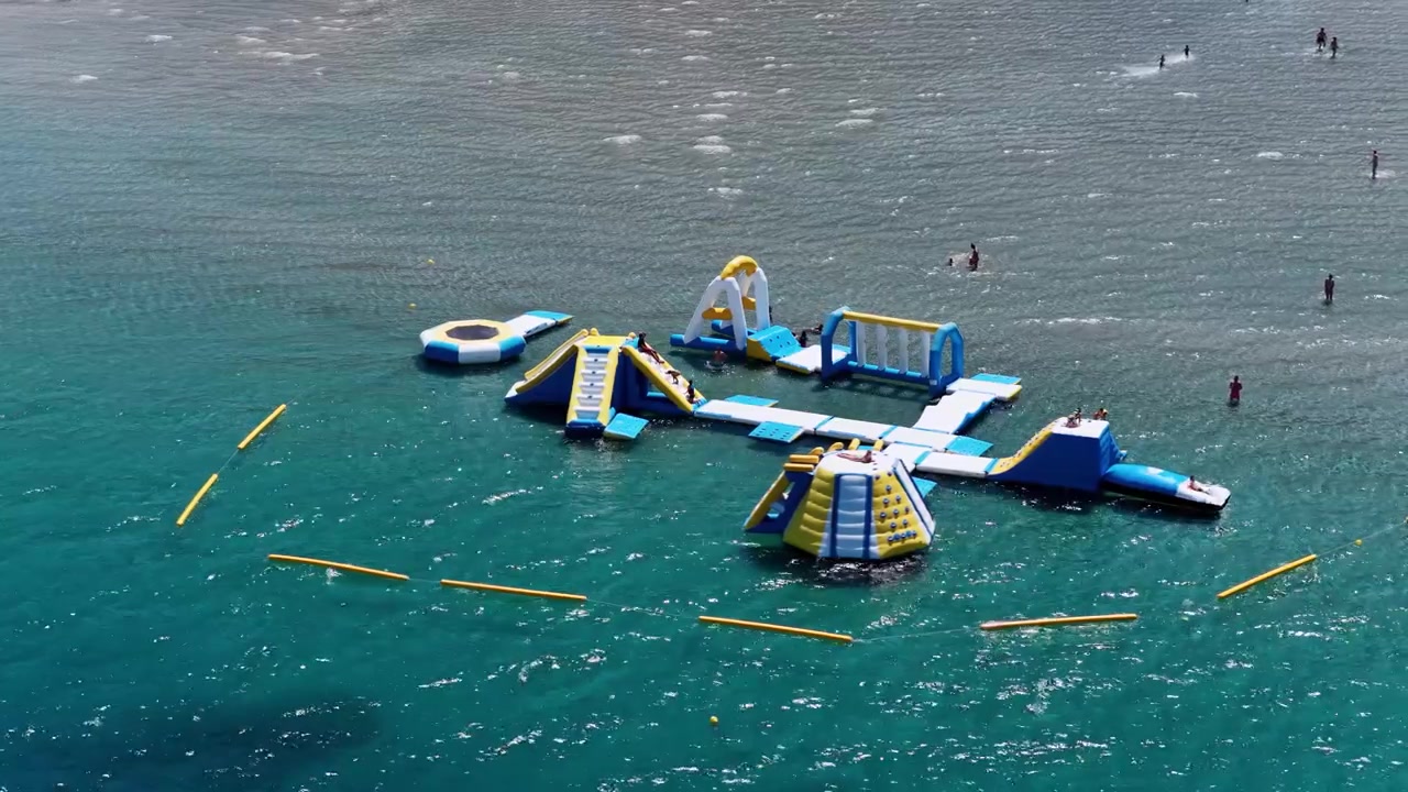 Close up aerial view of a colorful inflatable floating water park on the crystal clear turquoise sea water at Apraos beach in Corfu island Greece during summer.