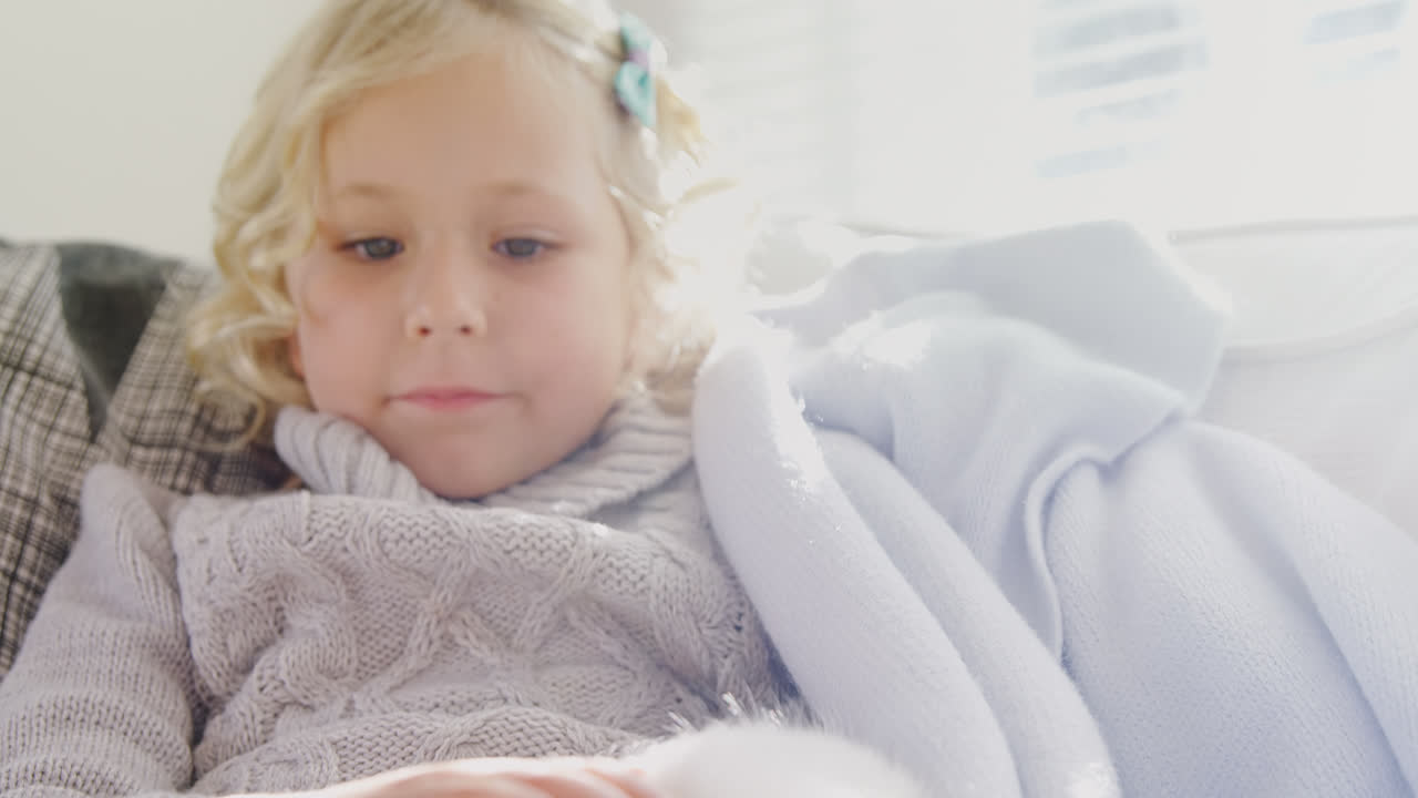 Bambina seduta sul divano che accarezza il suo gatto domestico 4K 4k