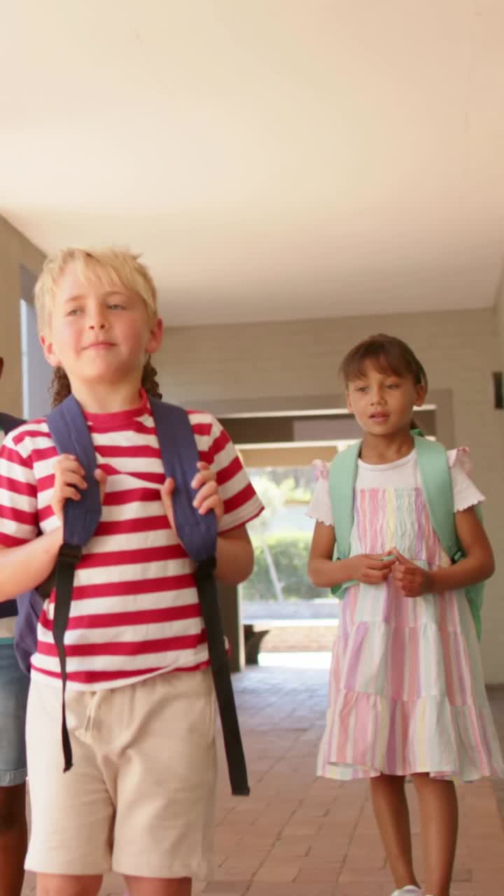 Vertical video: Leading blond boy in striped tee guiding kids with packs through porch to greenery