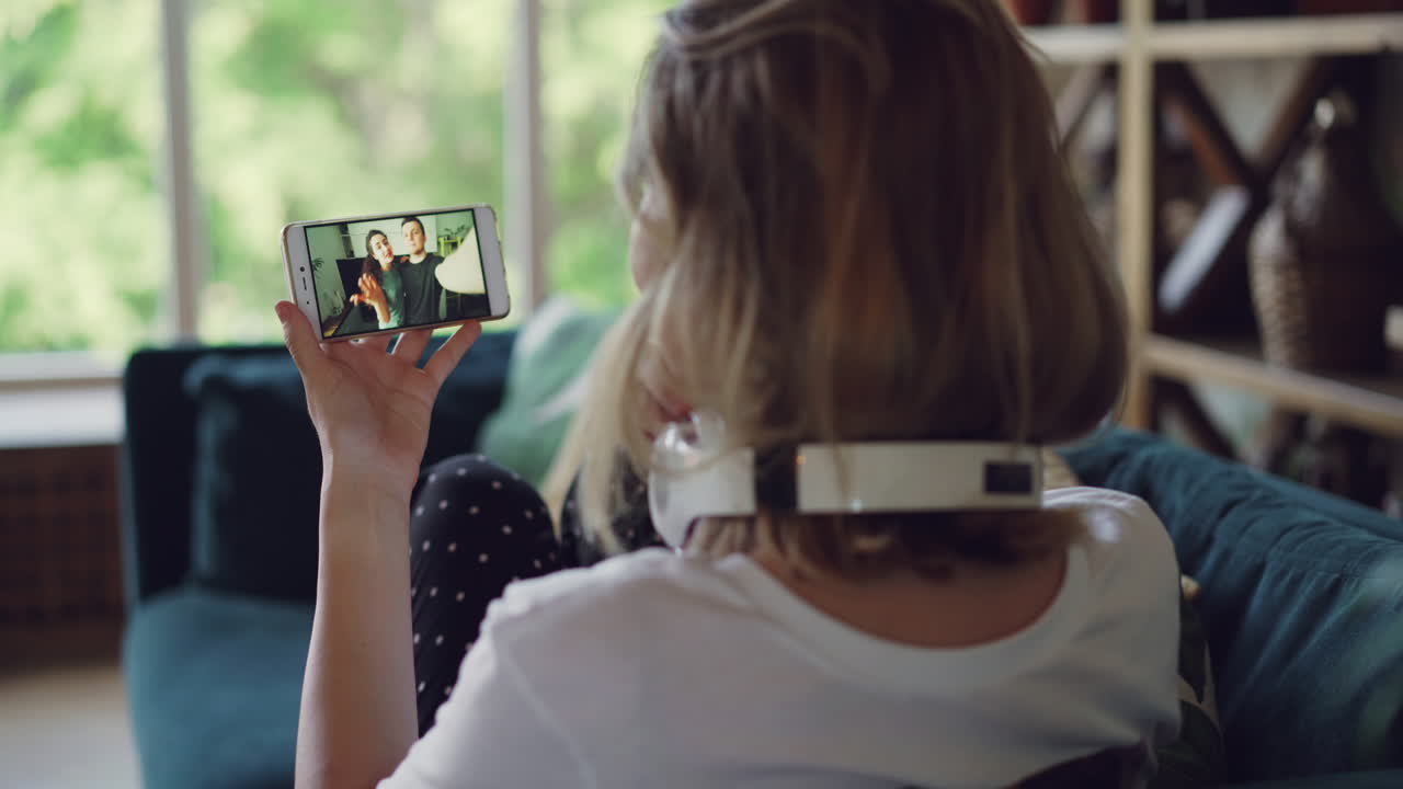 Woman watching video call on smartphone at home