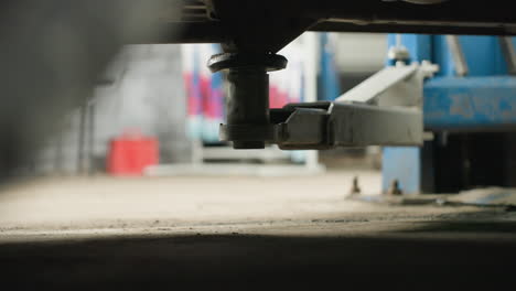 primer plano de un vehículo de elevación electrónica de automóviles en un taller de reparación de automóviles con equipos mecánicos azules visibles en el fondo, destacando la precisión y la estabilidad del mecanismo de elevación