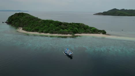 aerial view of a lush tropical island in the philippines with a boat on clear waters.