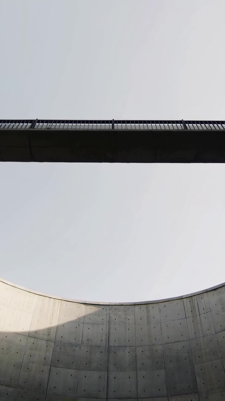 Vertikales Video: Neigende Kamera enthüllt Brücke mit Geländer über Schacht, folgt leichter Sonnenverschiebung.